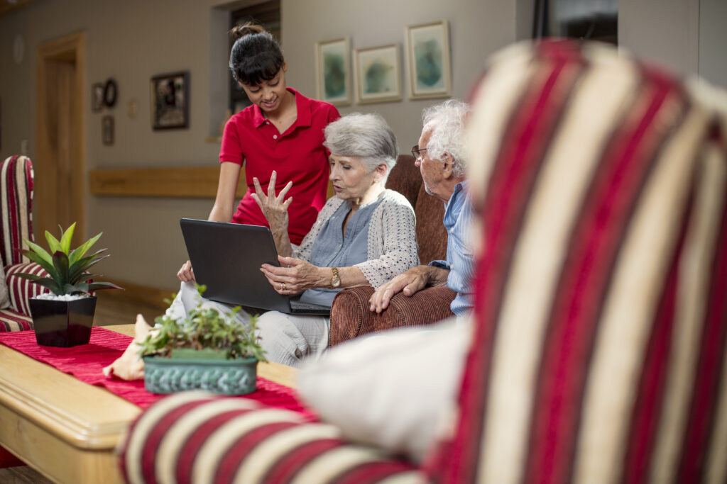 Frau hilft Senioren auf dem Sofa an einem Laptop